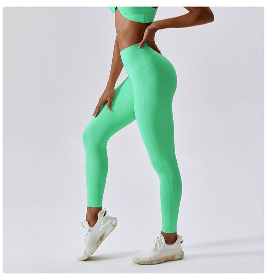 A photo of a woman wearing a stylish green 'BeYouAppleBottom' Crop Top paired with matching leggings, showcasing the epitome of style and functionality in activewear. The crop top features a flattering silhouette with the brand's iconic logo displayed on both front and back, while boasting padding for added support and a chic twist-hole design. This versatile ensemble transitions seamlessly from gym sessions to beach outings, embodying empowerment and self-expression.