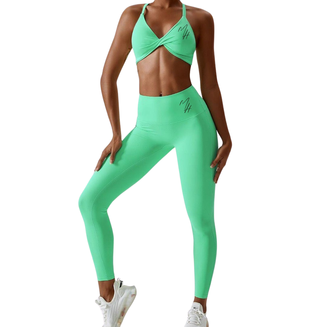 A photo of a woman wearing a stylish green 'BeYouAppleBottom' Crop Top paired with matching leggings, showcasing the epitome of style and functionality in activewear. The crop top features a flattering silhouette with the brand's iconic logo displayed on both front and back, while boasting padding for added support and a chic twist-hole design. This versatile ensemble transitions seamlessly from gym sessions to beach outings, embodying empowerment and self-expression.
