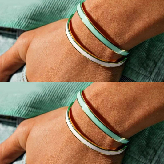 Two images, the first showing a wrist wearing a soft pink bangle with gold lining, and the second showing a wrist wearing a mint green bangle with gold lining. Both bangles have a gold-colored band with a heartfelt message.
